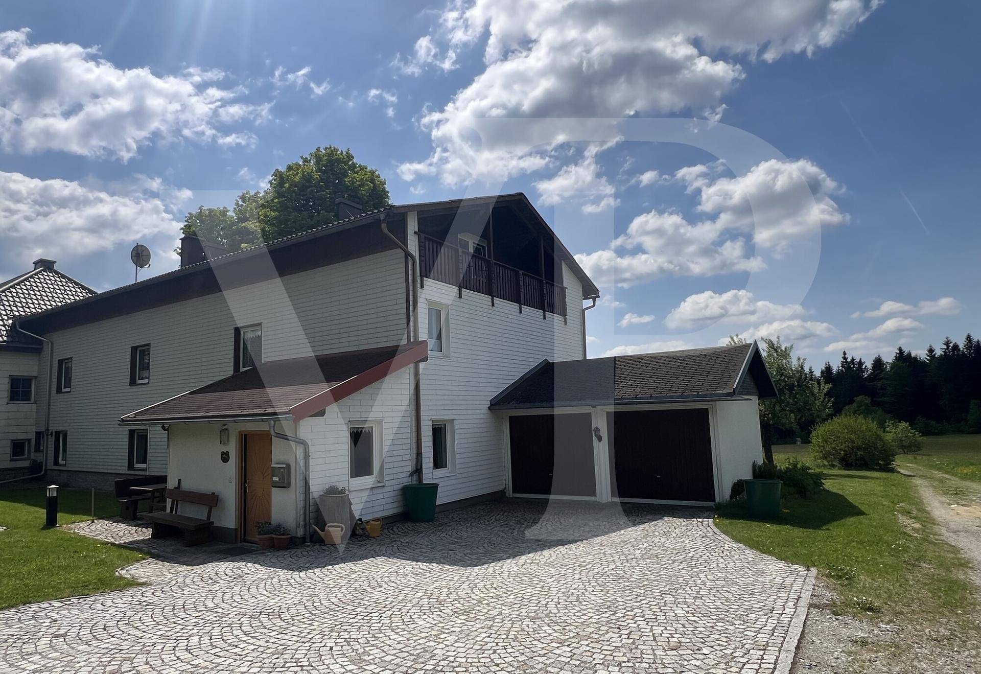 Seitenansicht des Hauses mit gepflasterter Auffahrt und integrierter Doppelgarage.