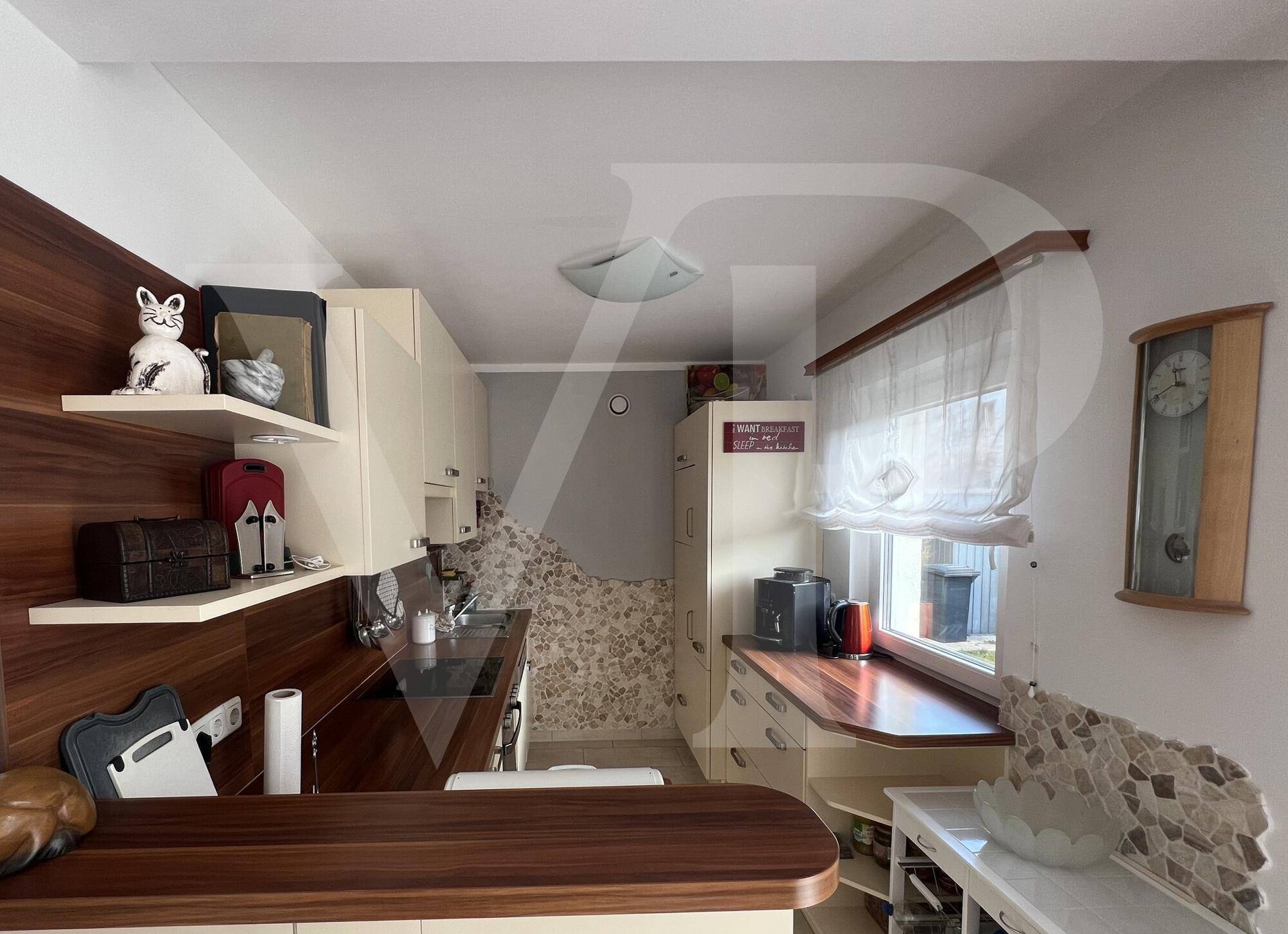 Gemütliche Küche mit Holzakzenten, Einbauküche und Fenster für natürliches Licht.