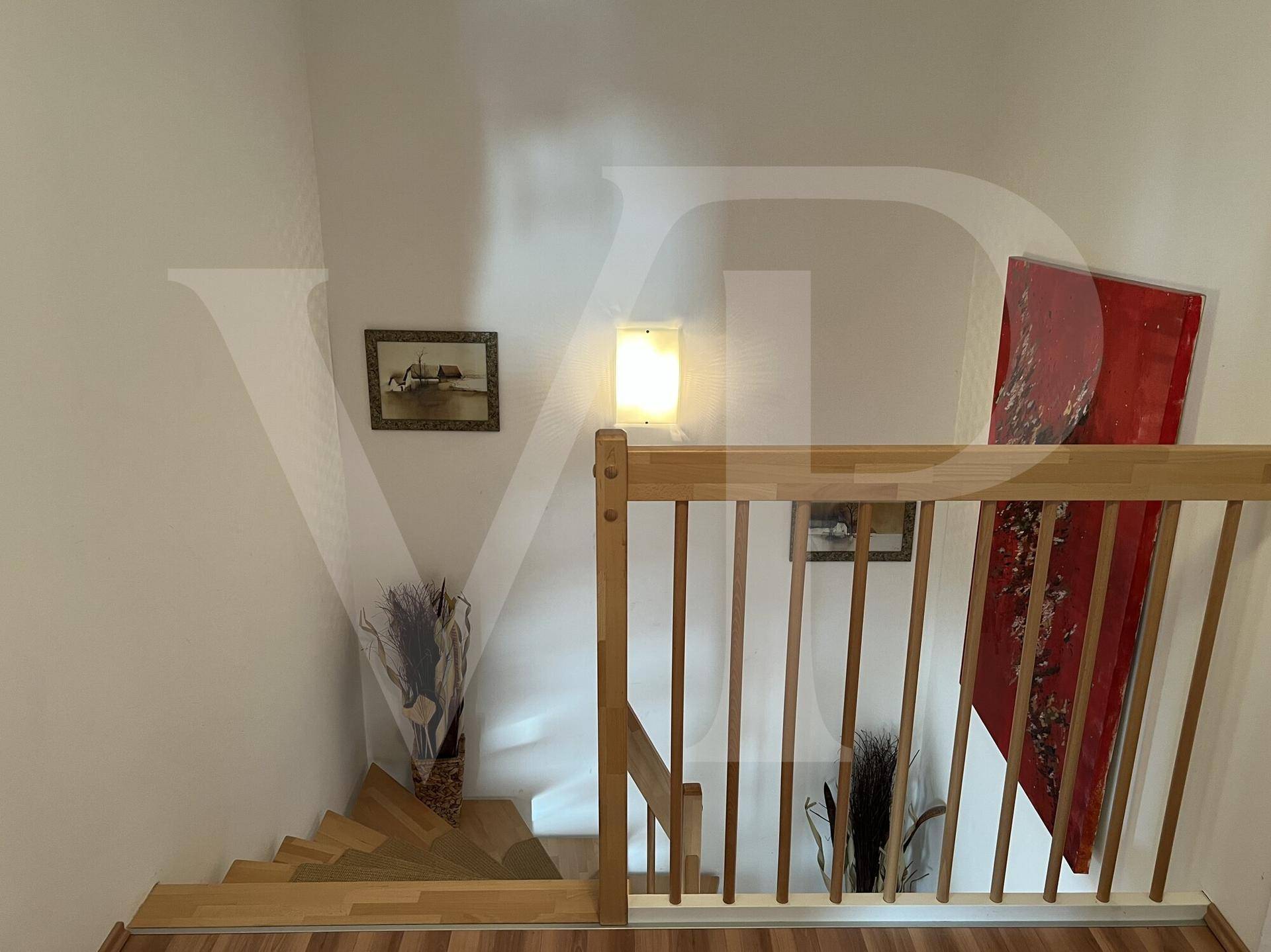 Oberer Treppenabsatz mit Holzgeländer und heller Wandgestaltung.