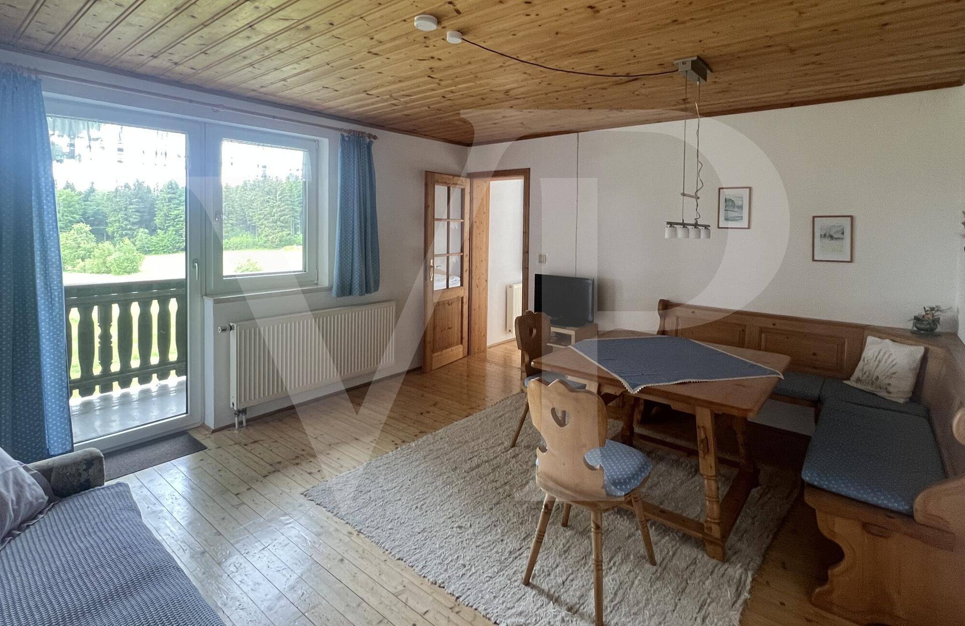 Wohn-Essbereich im Landhausstil mit Holzboden, Holzdecke und Zugang zum Balkon.