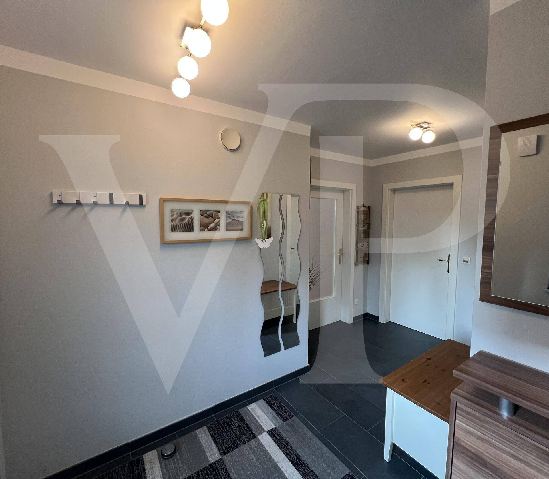 Heller Flur mit dunklem Fliesenboden, Spiegeln und Garderobe.