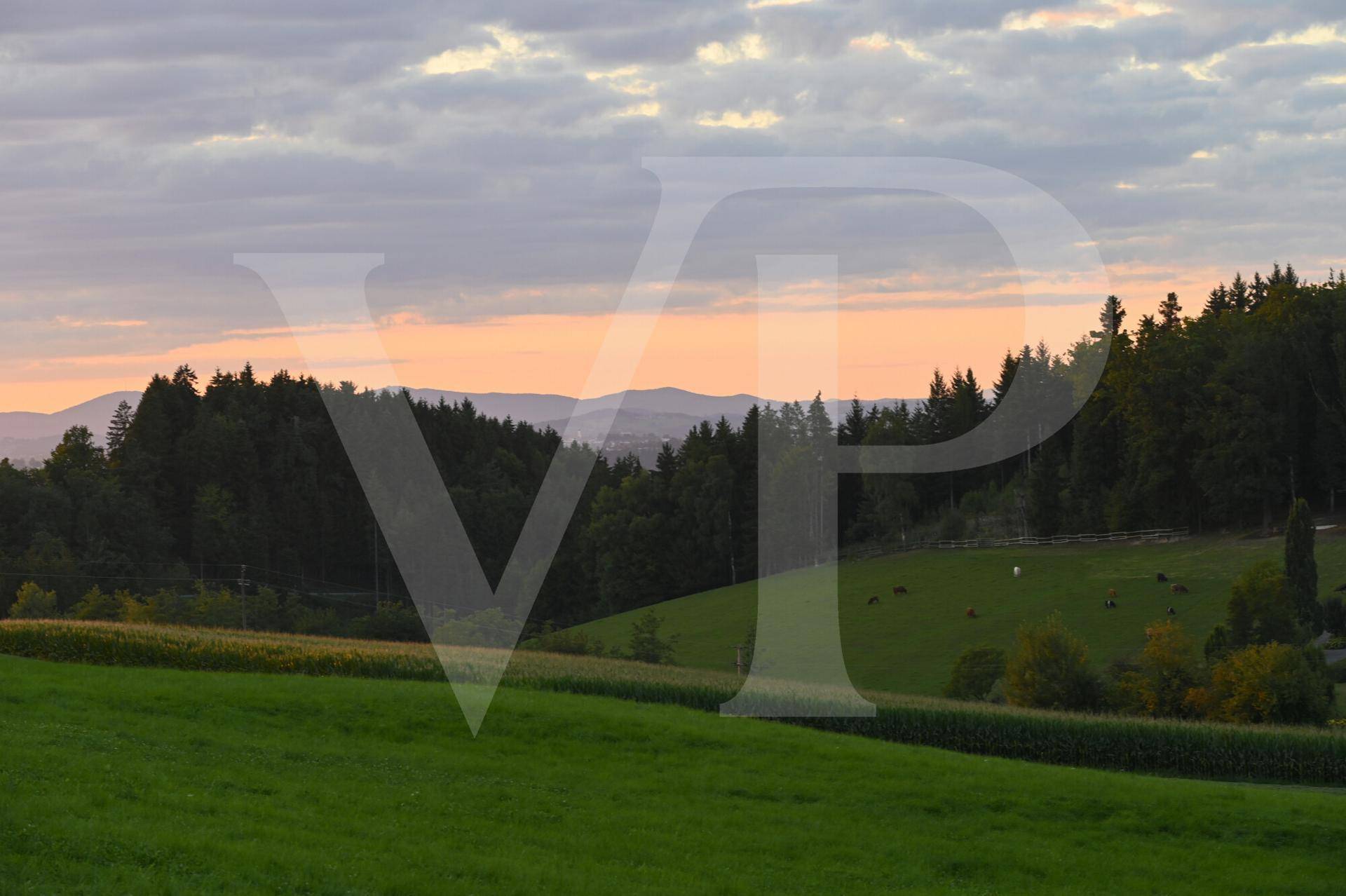Stimmungsvoller Sonnenuntergang über der ländlichen Landschaft mit Feldern und Wäldern.