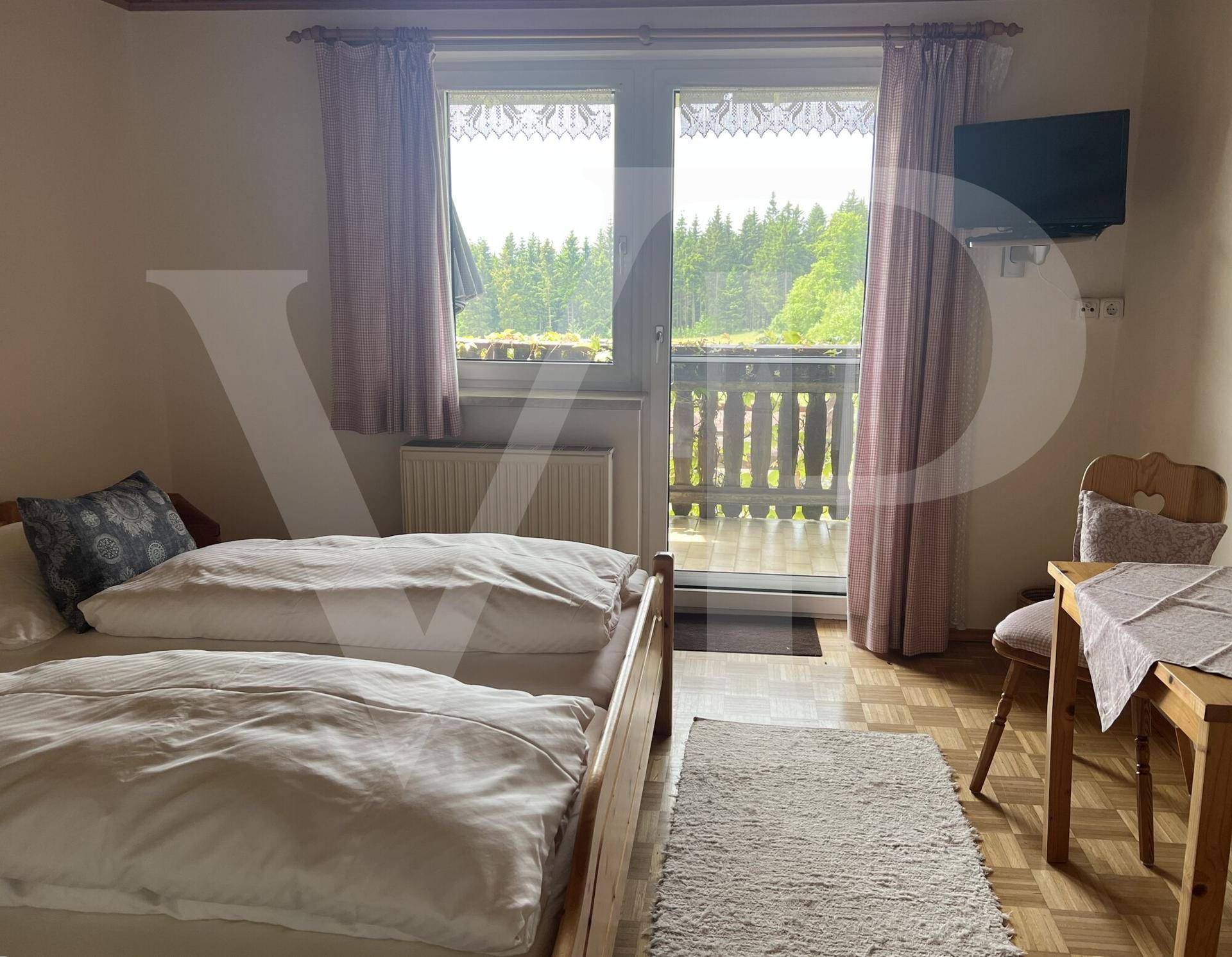 Gemütliches Schlafzimmer mit zwei Betten, Holzboden und direktem Zugang zum Balkon.