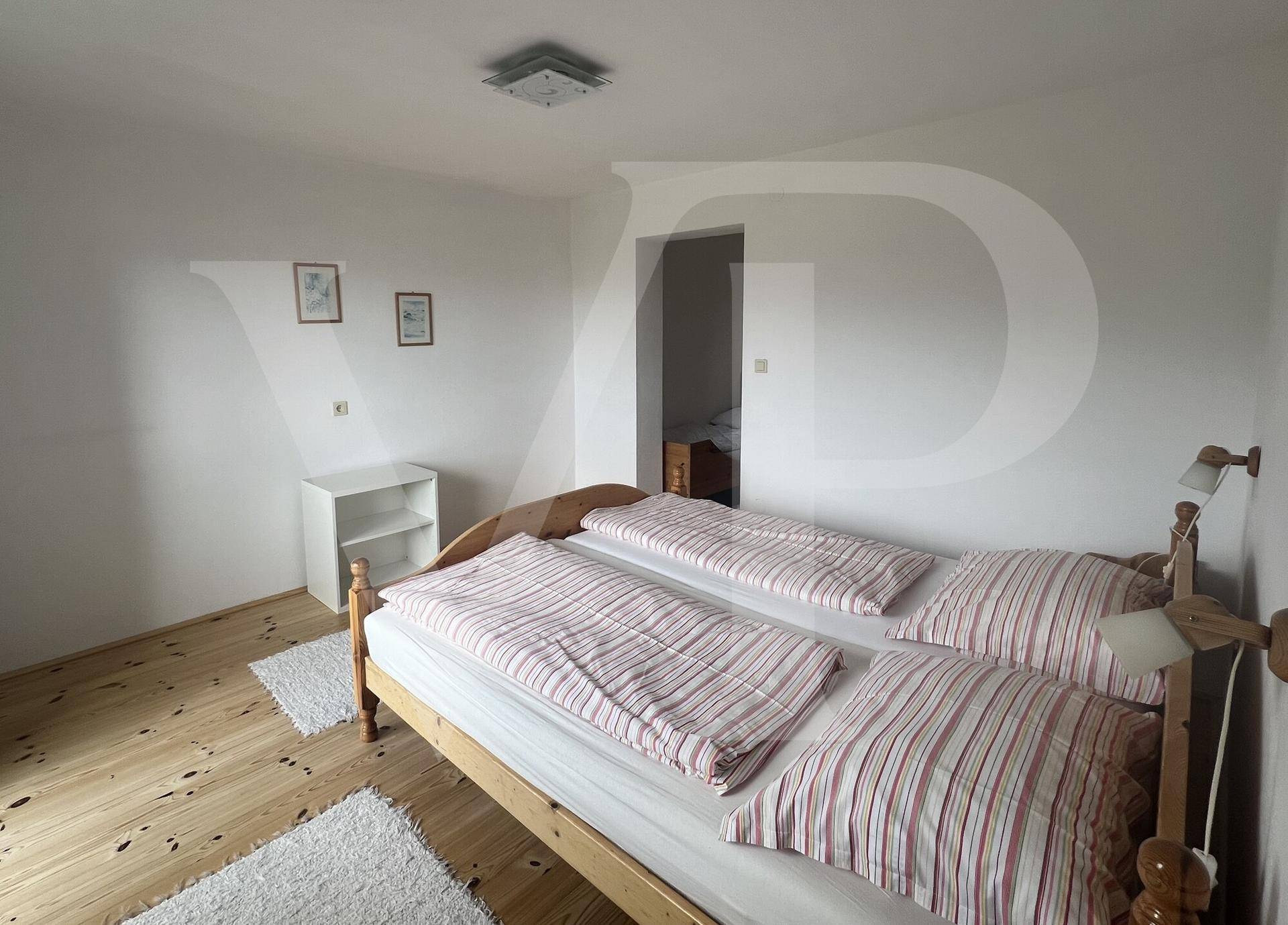 Einfaches Schlafzimmer mit zwei Betten, Holzboden und weiß gestrichenen Wänden.