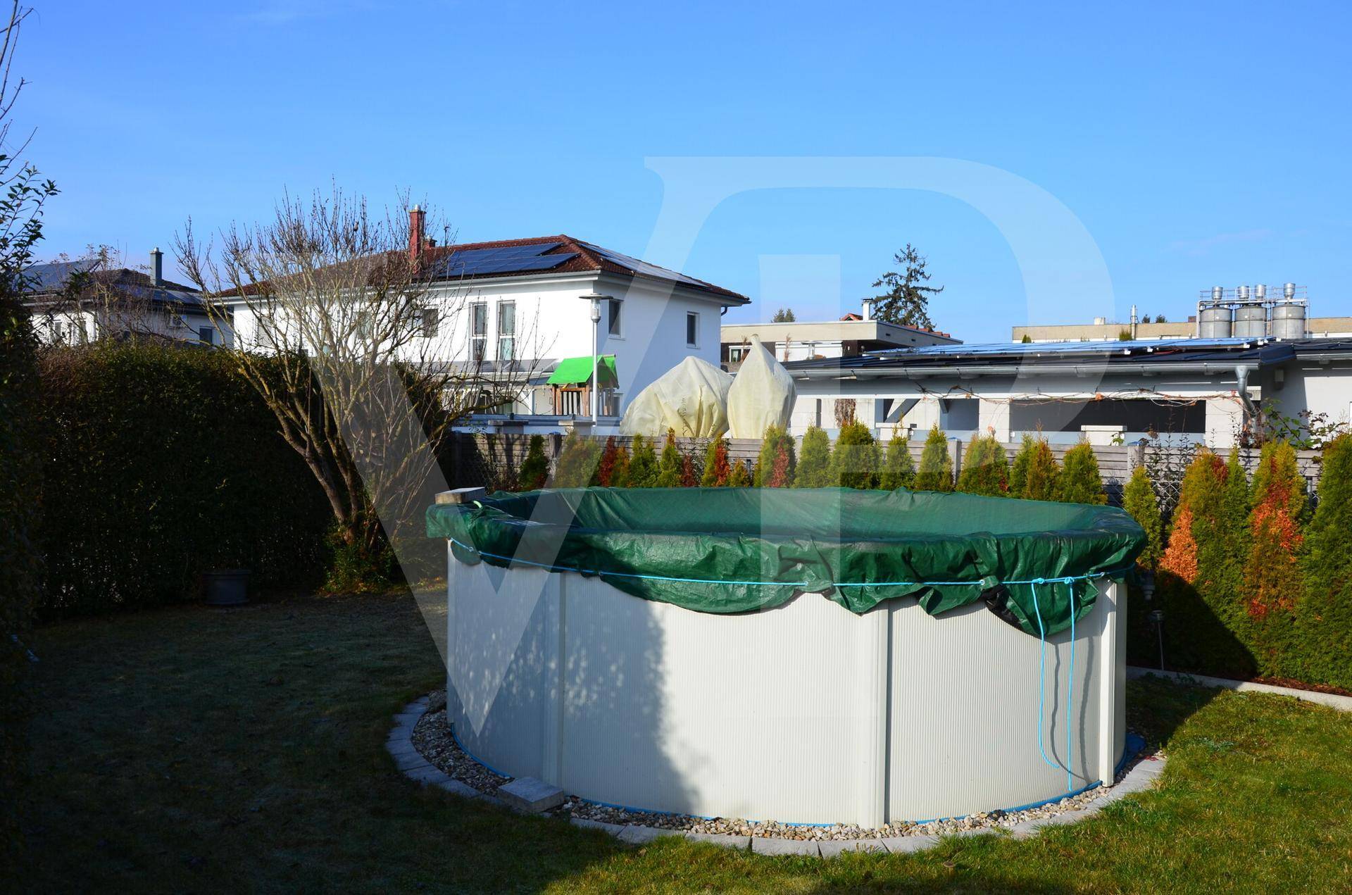 Garten mit einem oberirdischen Pool, umgeben von Rasen und Hecken.