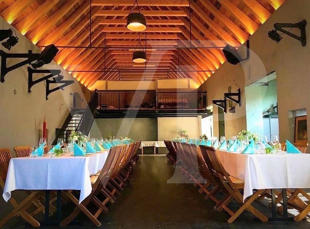 Festlich geschmückter Saal mit langen Esstischen und Blick auf die obere Empore.