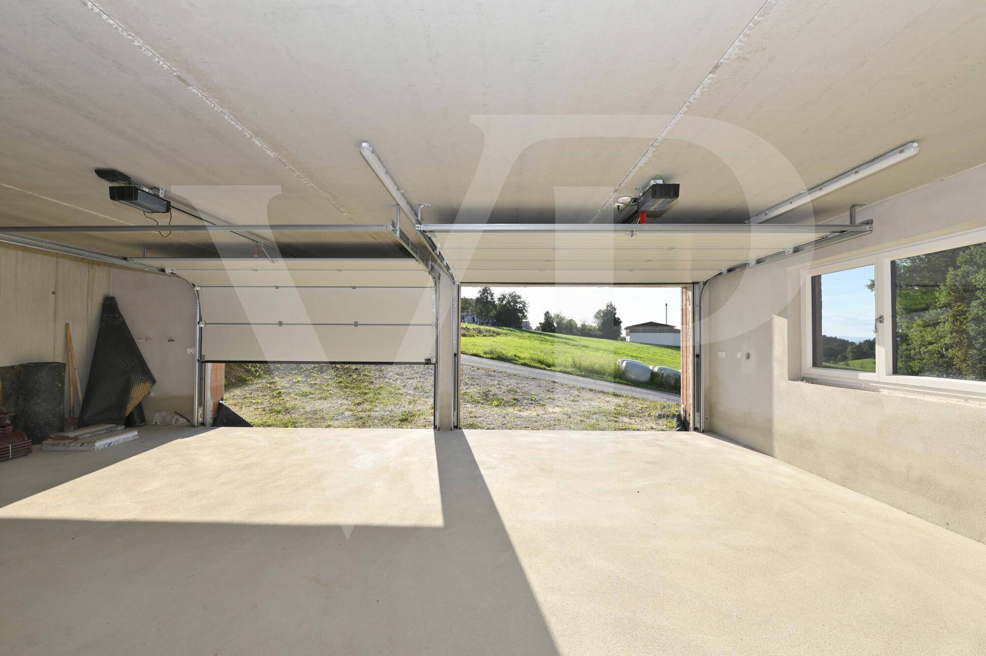Doppelgarage mit zwei Rolltoren und Fenster, das Tageslicht hereinlässt.