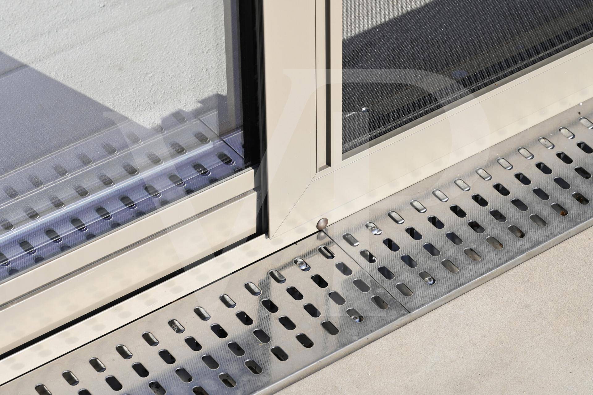 Detailaufnahme eines modernen Entwässerungssystems vor einer Glasschiebetür.