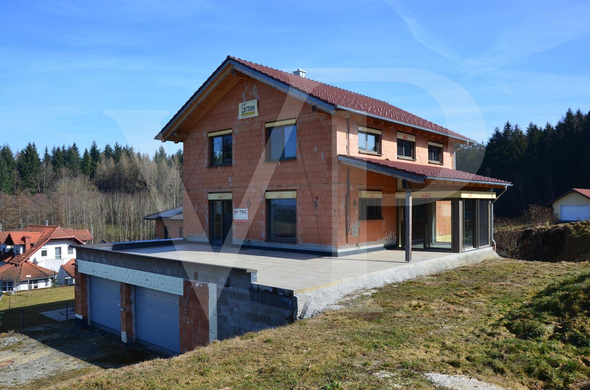 Rohbau eines Einfamilienhauses mit großer Terrasse und Blick auf die Umgebung.