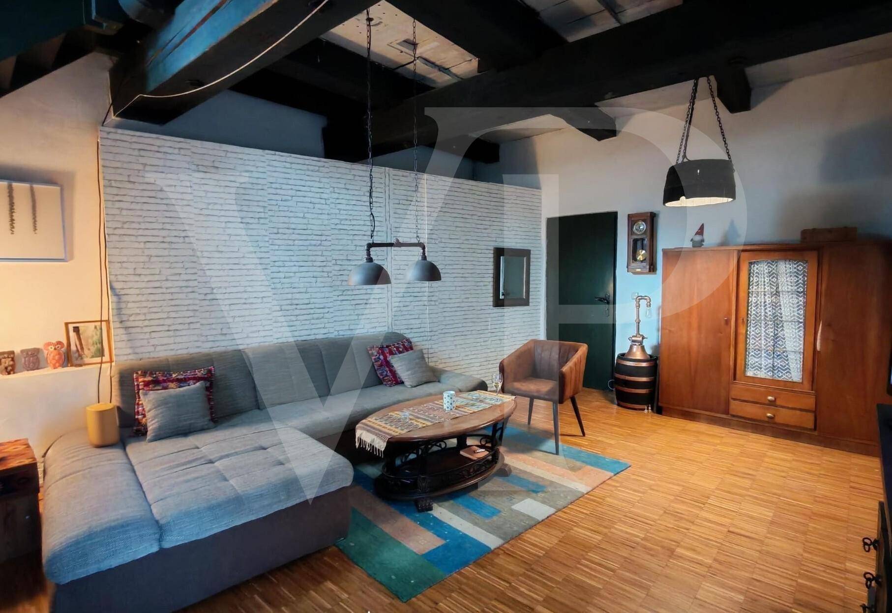 Wohnzimmer mit Ecksofa, Couchtisch und einer Akzentwand in weißer Ziegeloptik.