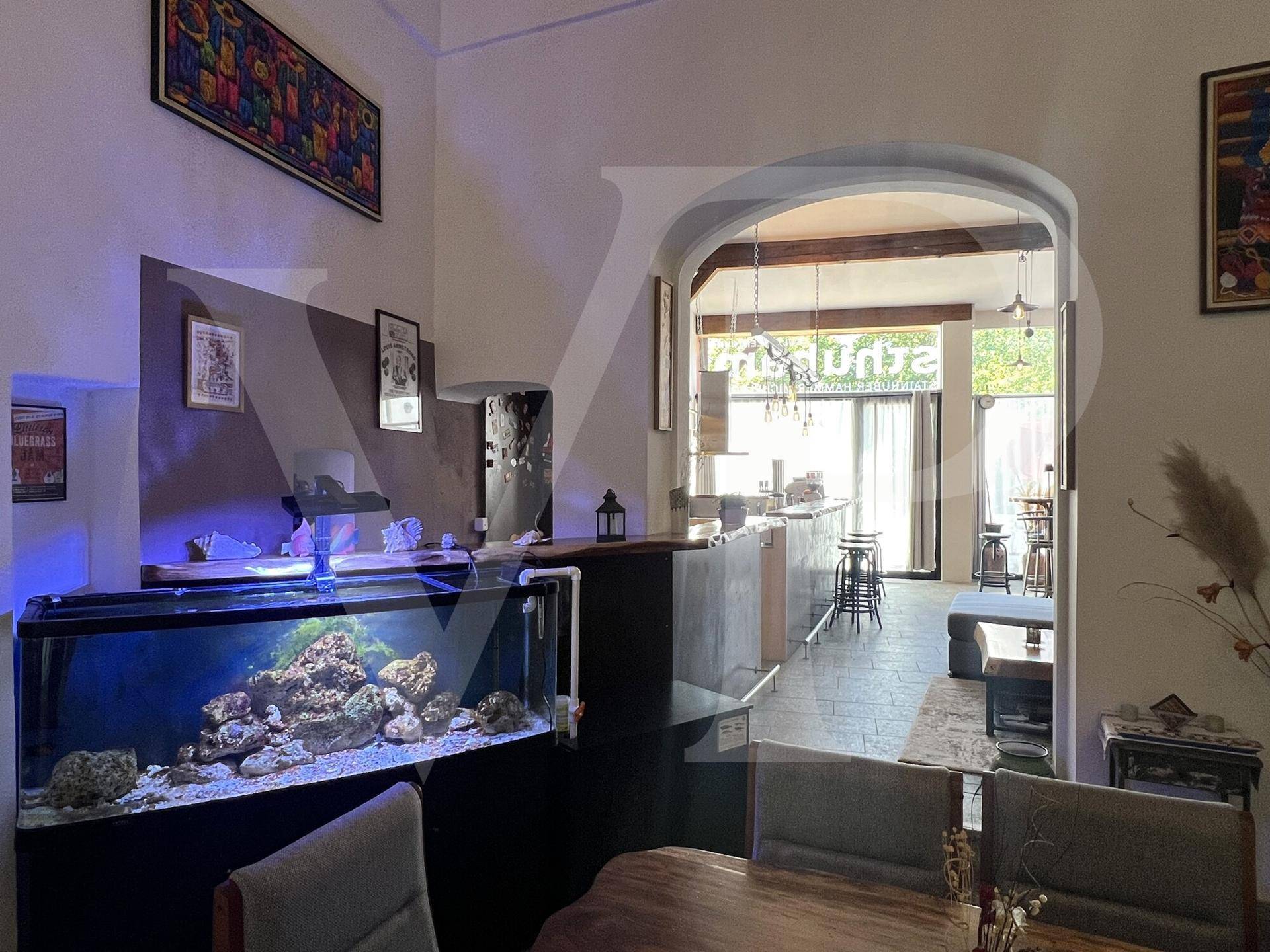 Blick durch einen Bogen in den Barbereich, mit einem großen Aquarium im Vordergrund.