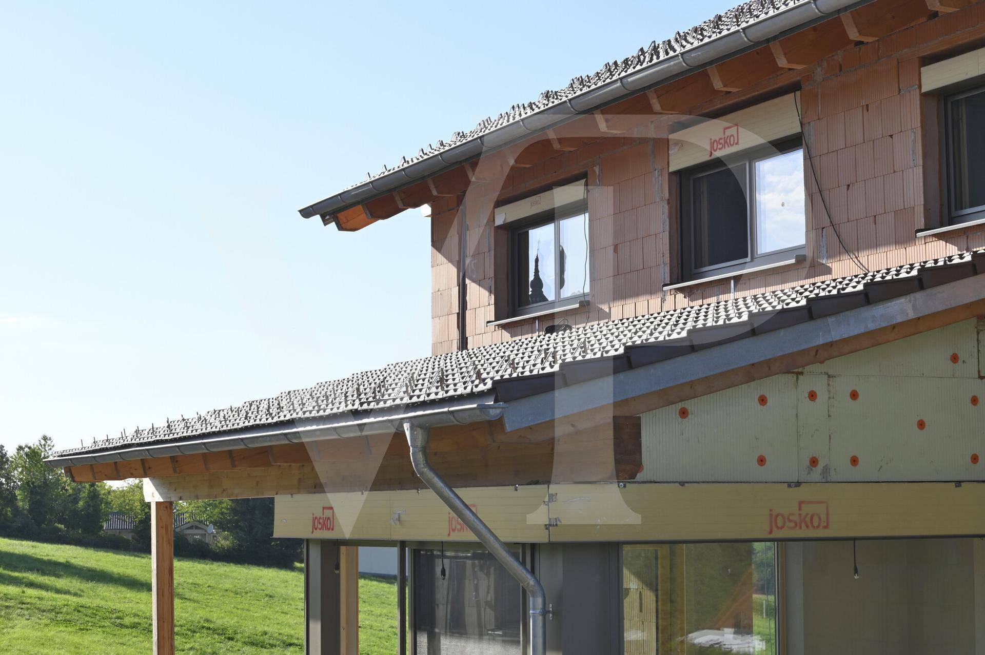 Detailansicht des Daches und der Fassade im Bau mit sichtbaren Holzelementen.