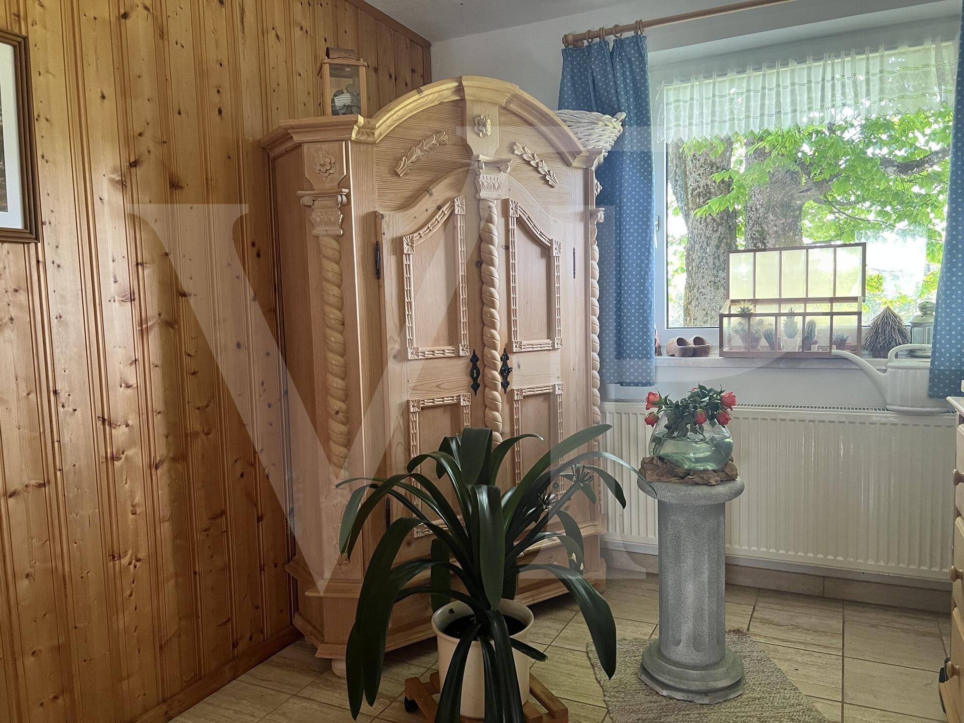 Zimmer mit Holzvertäfelung, traditionellem Holzschrank und Fenster mit Blick nach draußen.