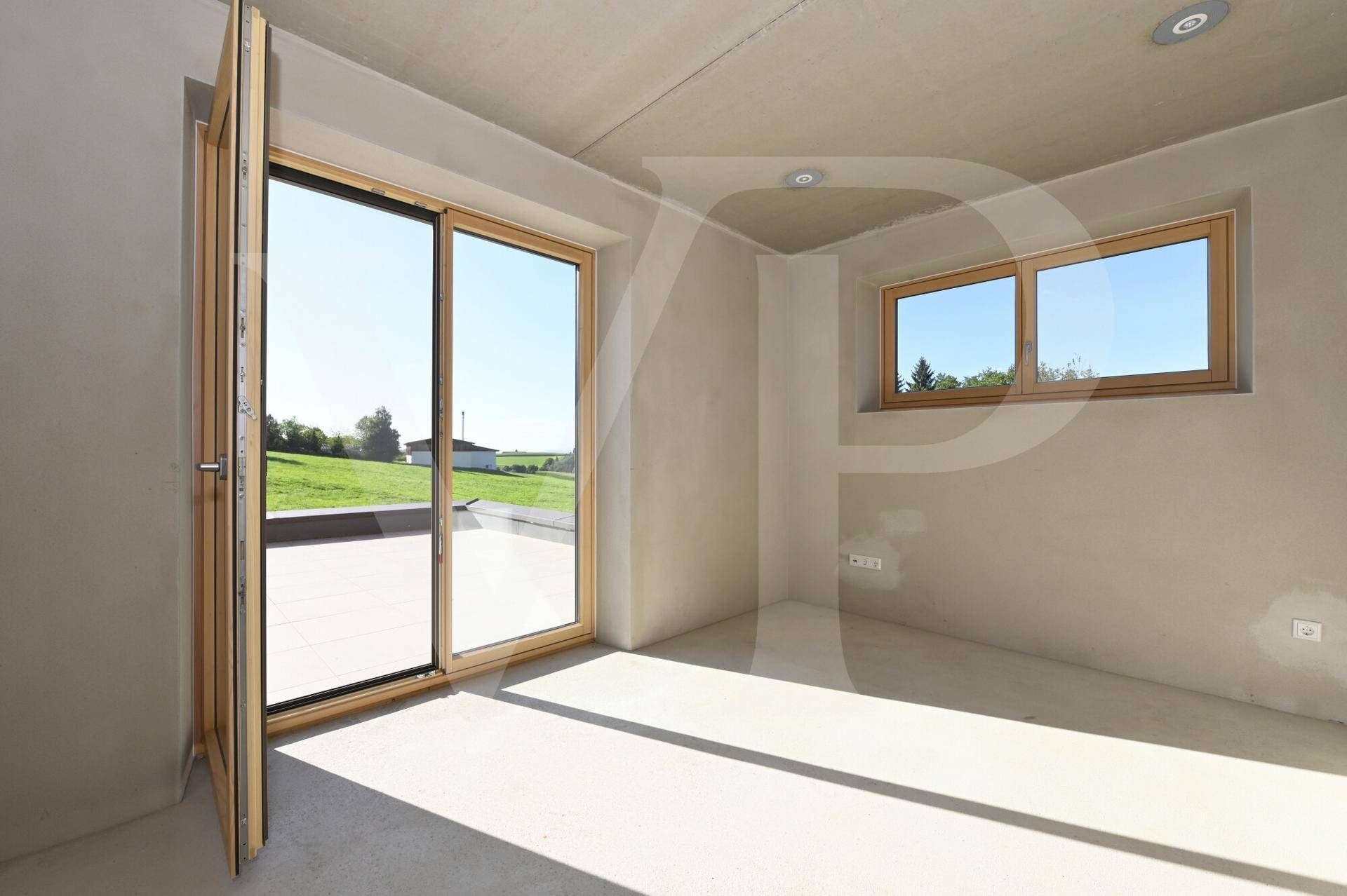 Unfertiger Raum mit Schiebetür zum Außenbereich und Fenster mit Blick ins Grüne.