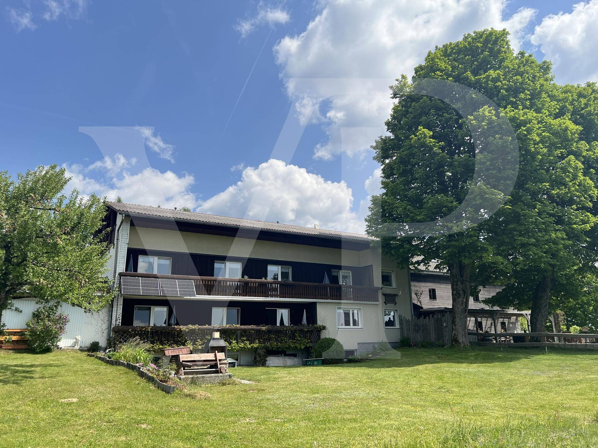 Weitläufiger Garten mit altem Baumbestand und Blick auf die umliegende Naturlandschaft.