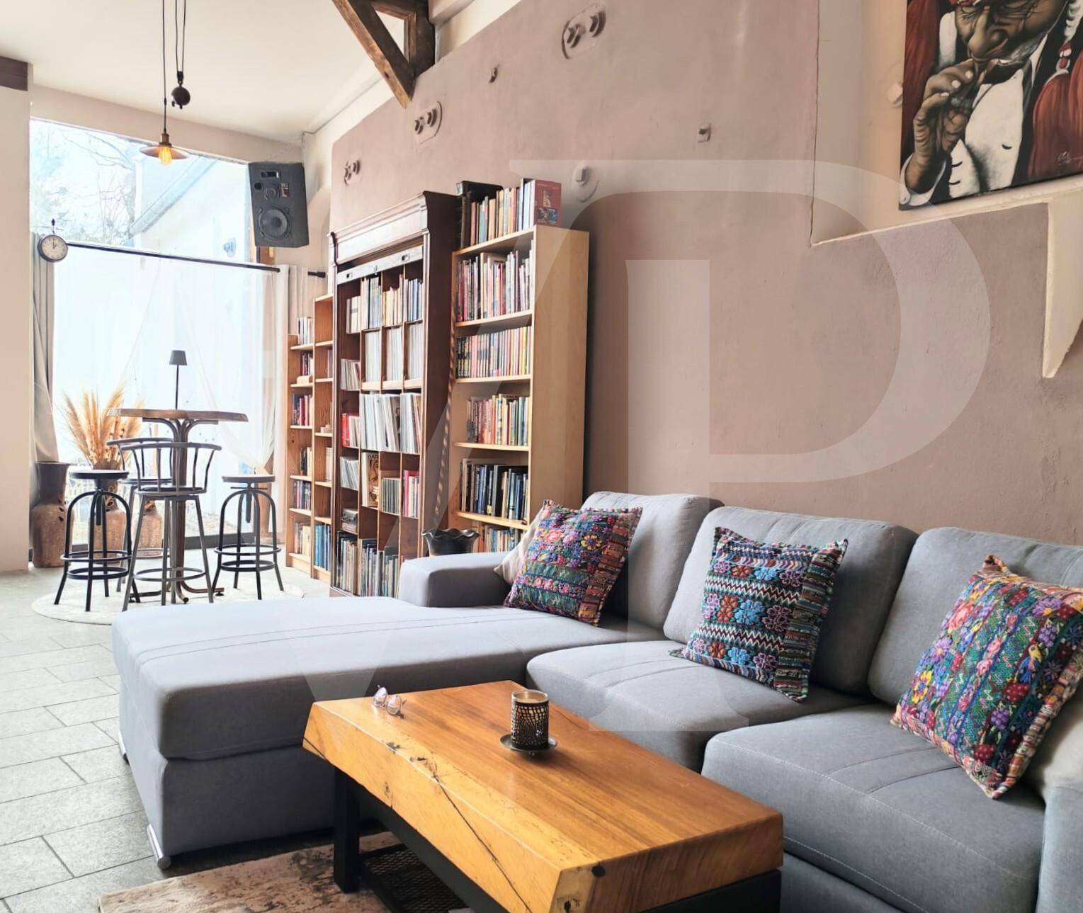 Geräumiger Wohnbereich mit großem Ecksofa, Holztisch und umfangreicher Büchersammlung.