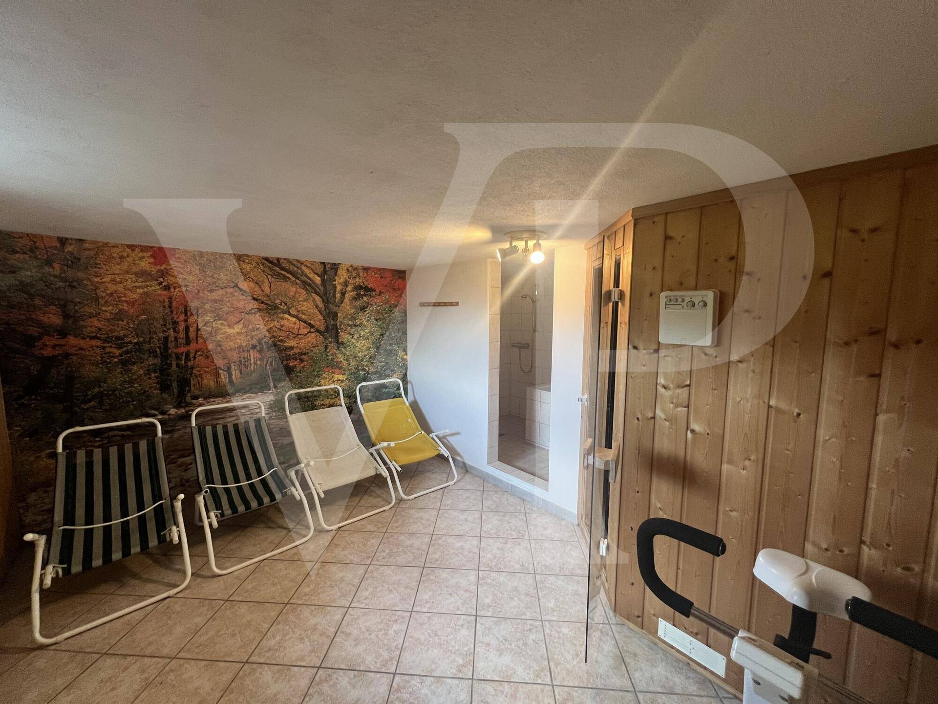 Entspannungsbereich mit Liegestühlen, Wandtapete und Zugang zur Sauna.