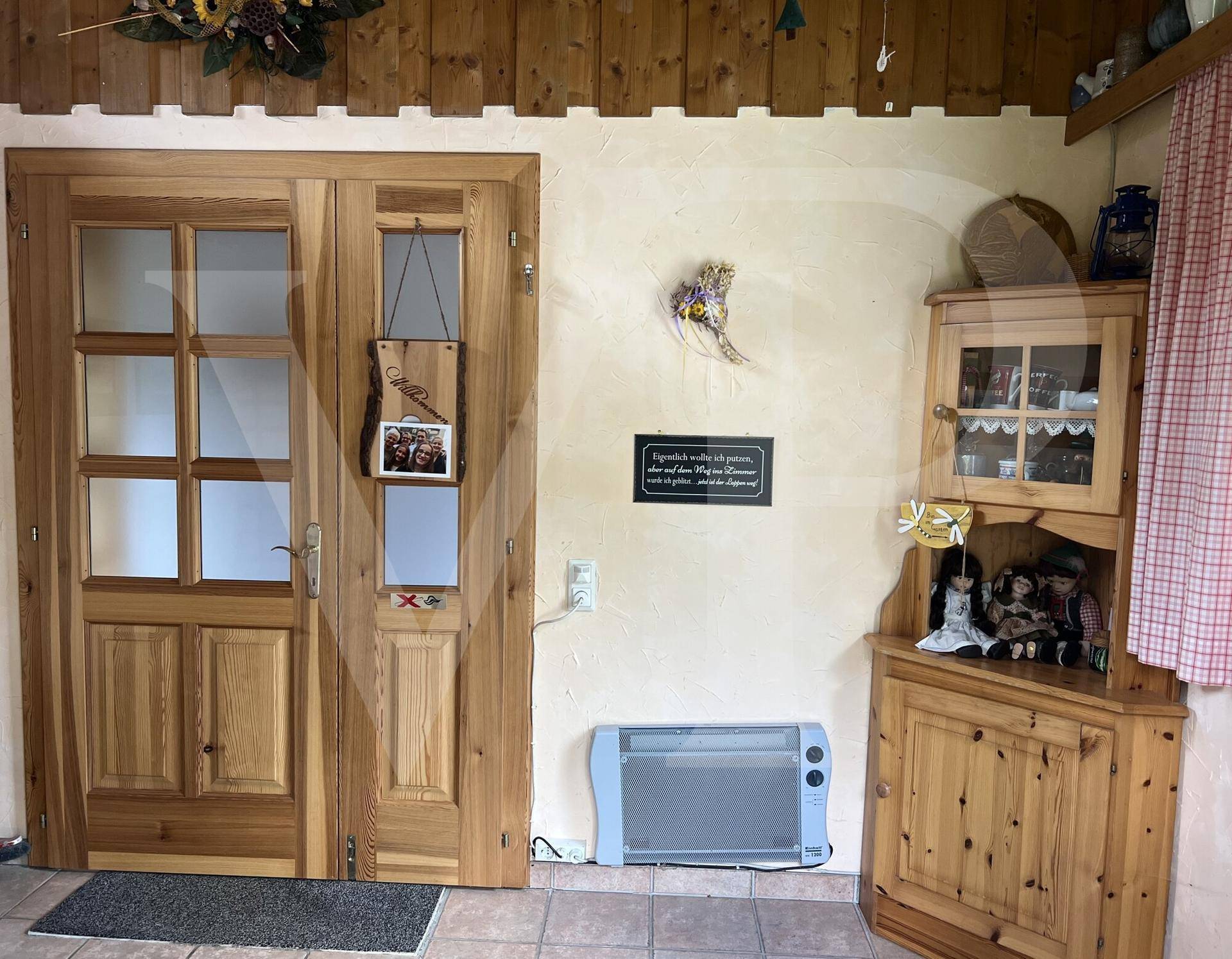 Gemütlicher Eingangsbereich mit Holztüren, Fliesenboden und traditionellem Eckschrank.