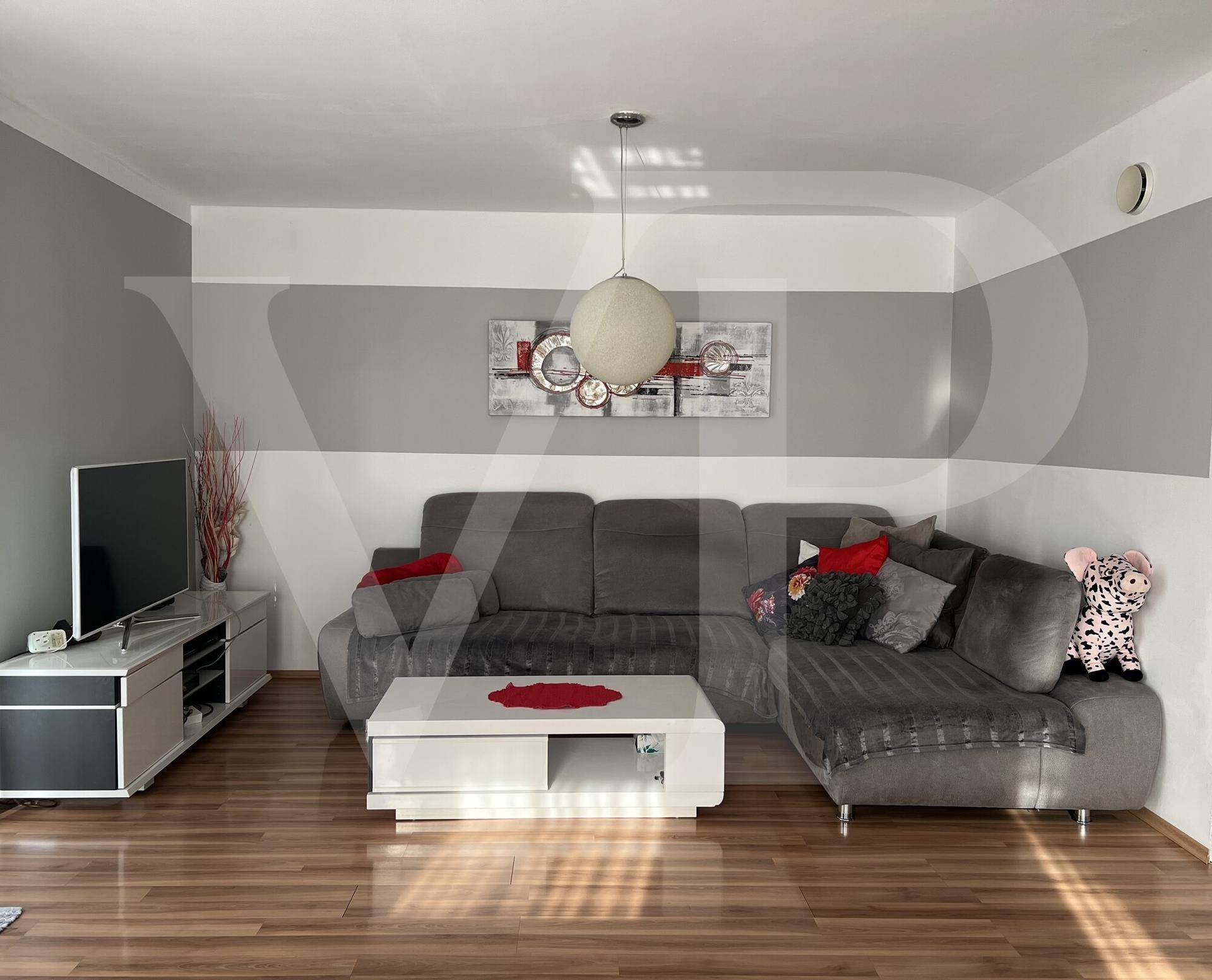 Modern eingerichtetes Wohnzimmer mit großem Sofa, Holzboden und stilvoller Dekoration.