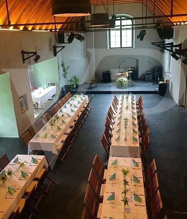 Großer Saal, festlich gedeckt mit langen Tischen, weißen Tischdecken und blauen Servietten.
