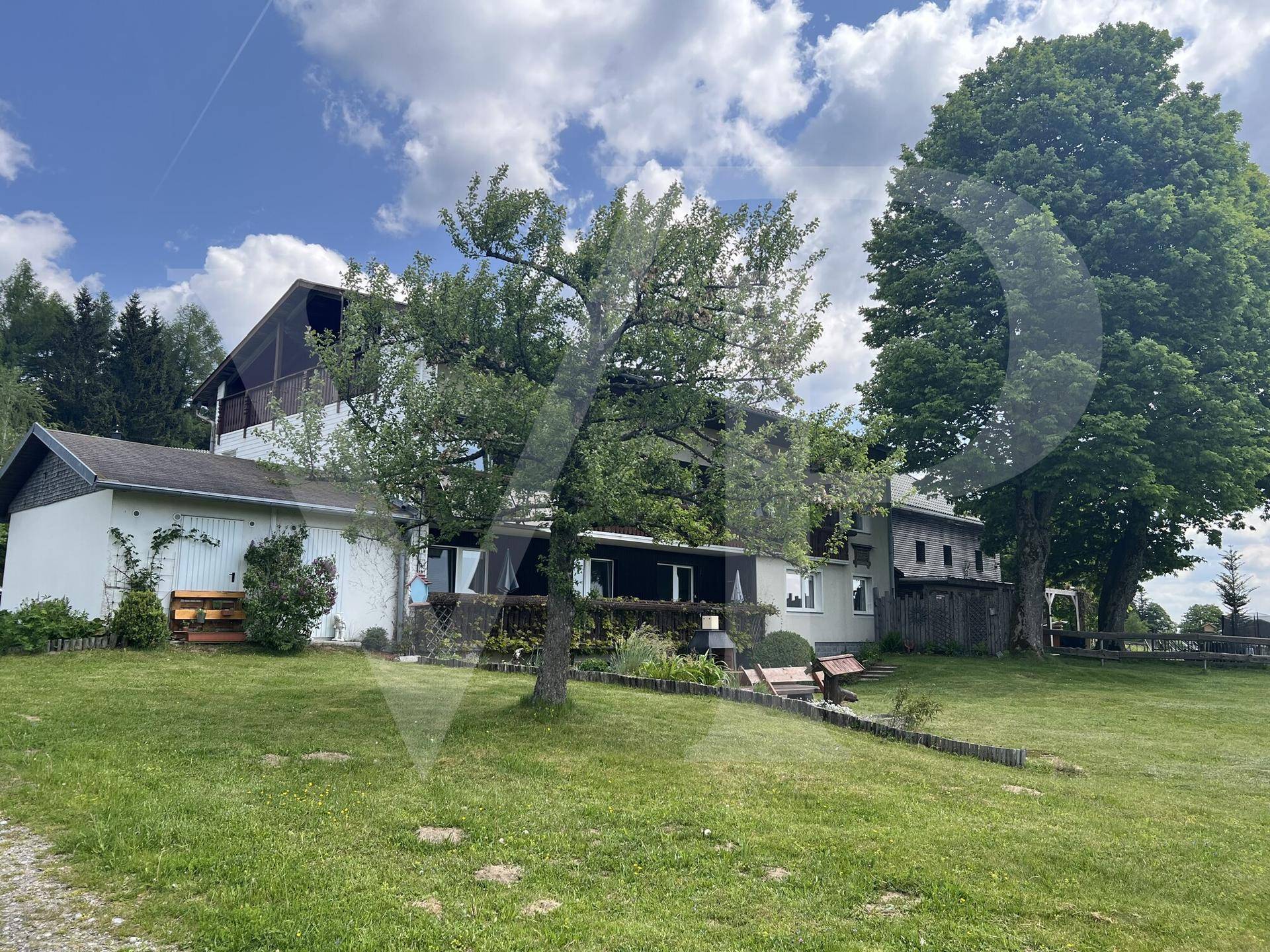 Rückansicht des Hauses mit großem Garten, altem Baumbestand und ländlicher Umgebung.