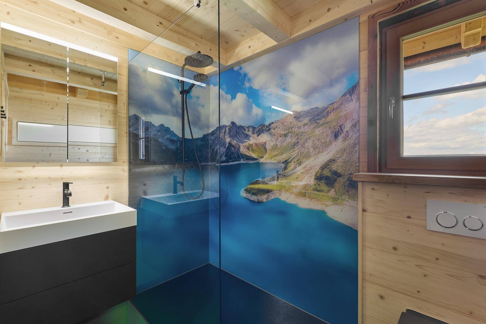 Modernes Badezimmer in einem Holzchalet mit Dusche und Bergsee-Motiv an der Wand.