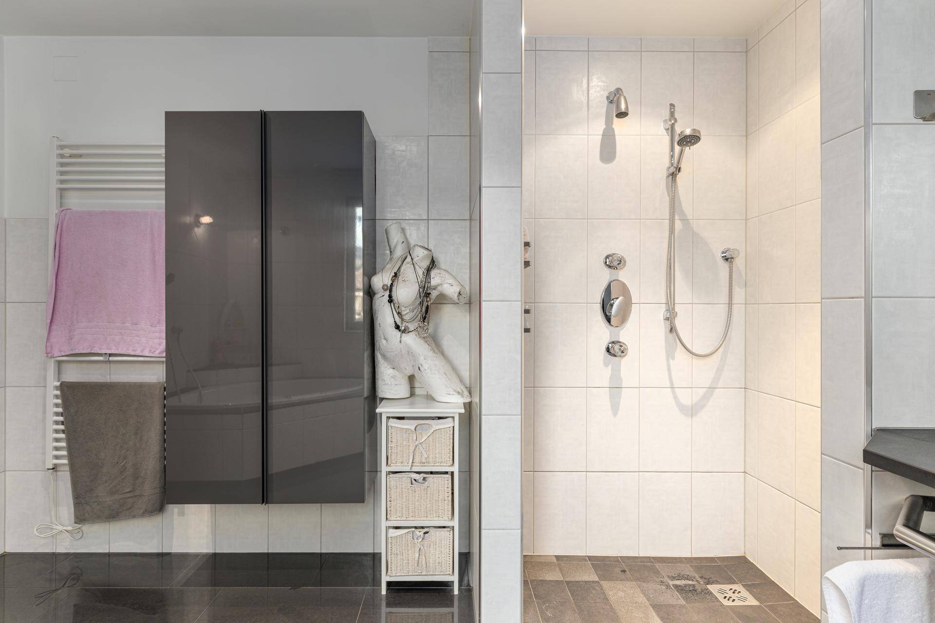 Modernes Badezimmer mit ebenerdiger Dusche, beheiztem Handtuchhalter und eleganten Fliesen.