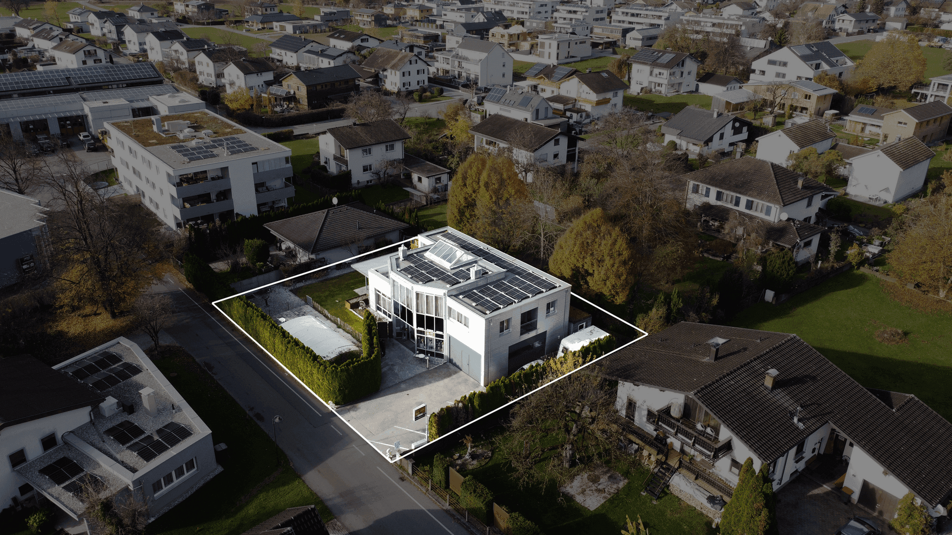 Luftaufnahme des modernen Hauses mit Solaranlage und Pool in einer grünen Wohnsiedlung.