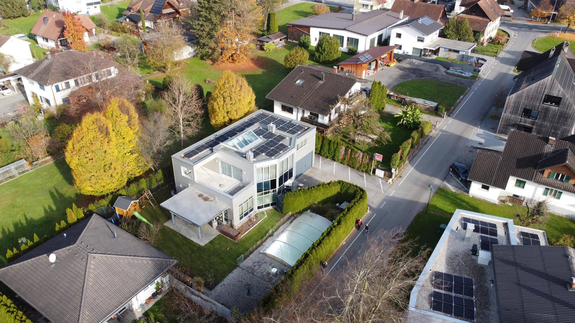 Luftaufnahme des modernen Wohnhauses mit Solaranlage, Pool und angrenzender Straße.