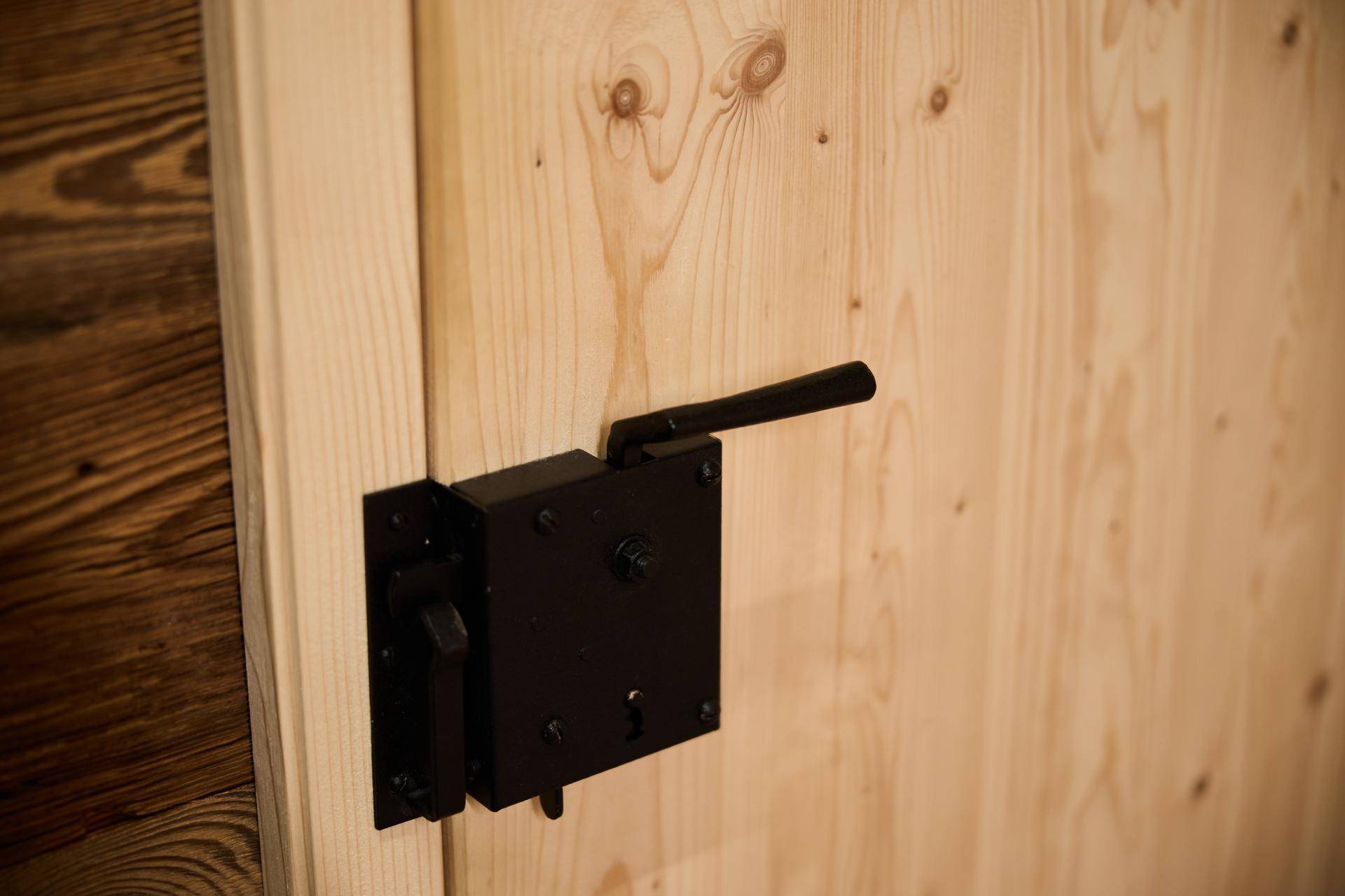 Detailaufnahme einer Holztür mit rustikalem schwarzen Beschlag in einem Holzchalet.