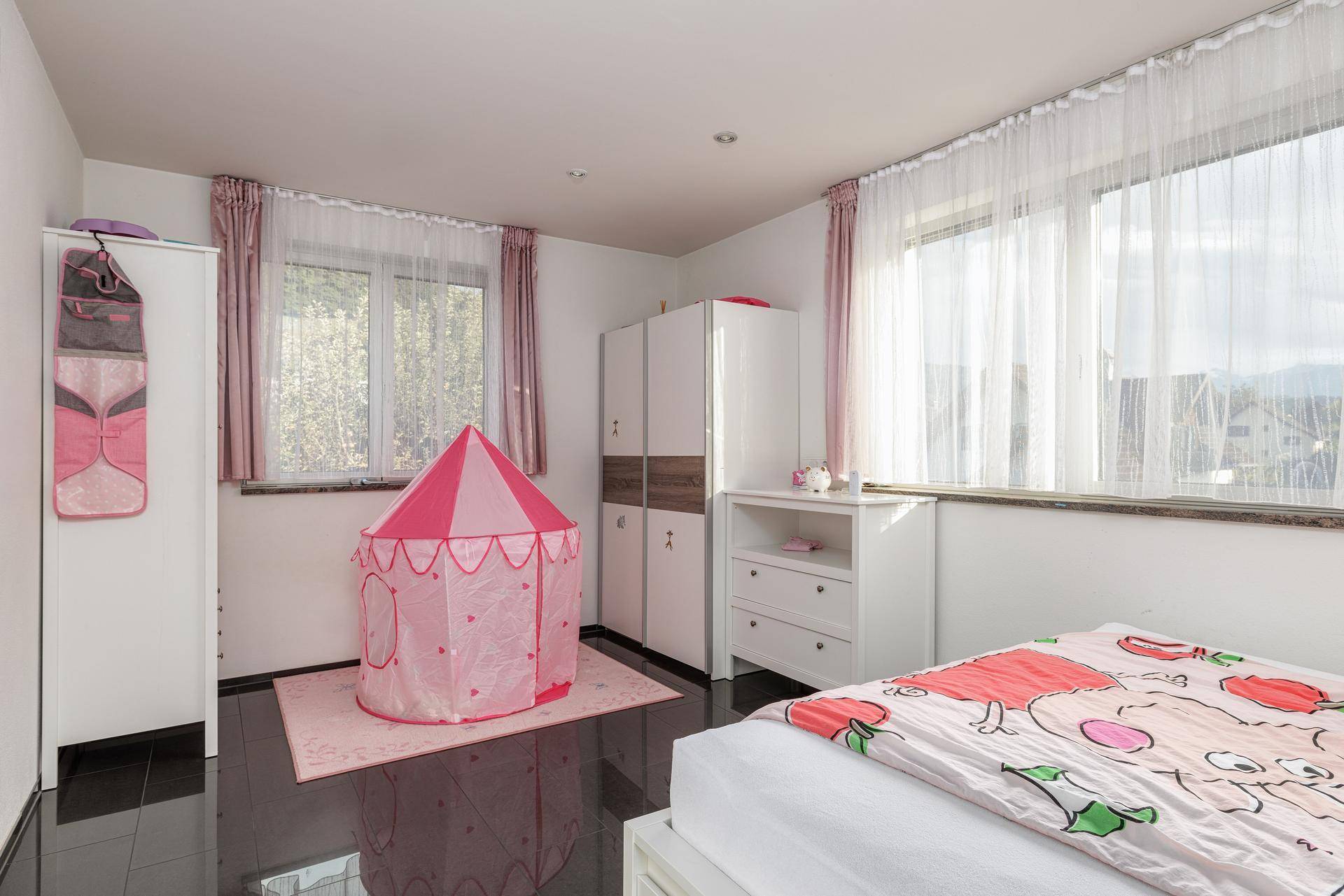 Kinderzimmer mit Spielzelt, Schränken und großen Fenstern für viel Tageslicht und Helligkeit.