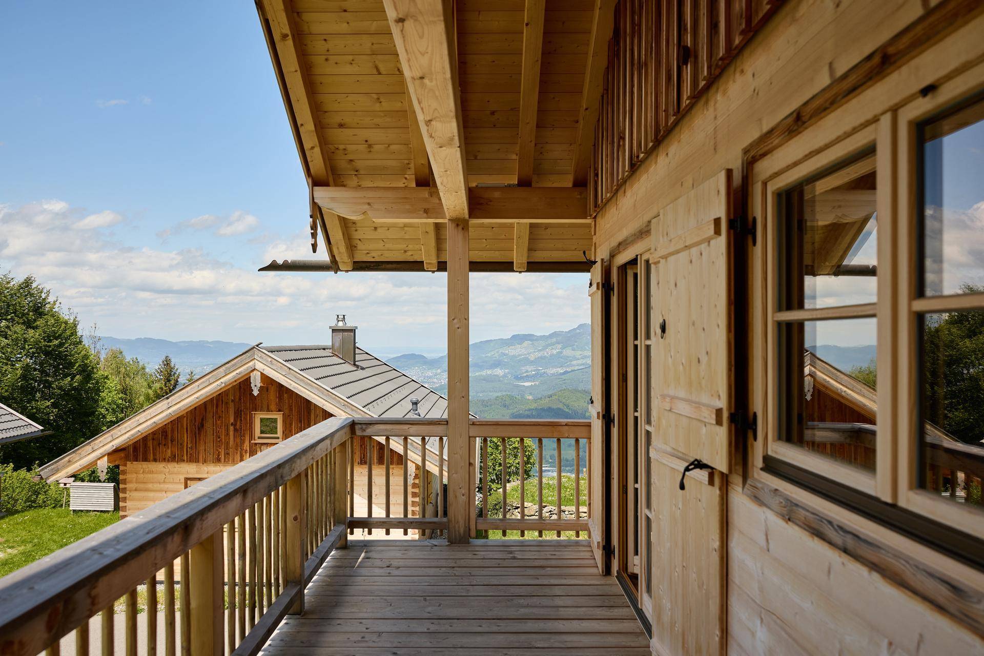Holzbalcon mit Bergblick und traditionellem Geländer an einem Chalet.