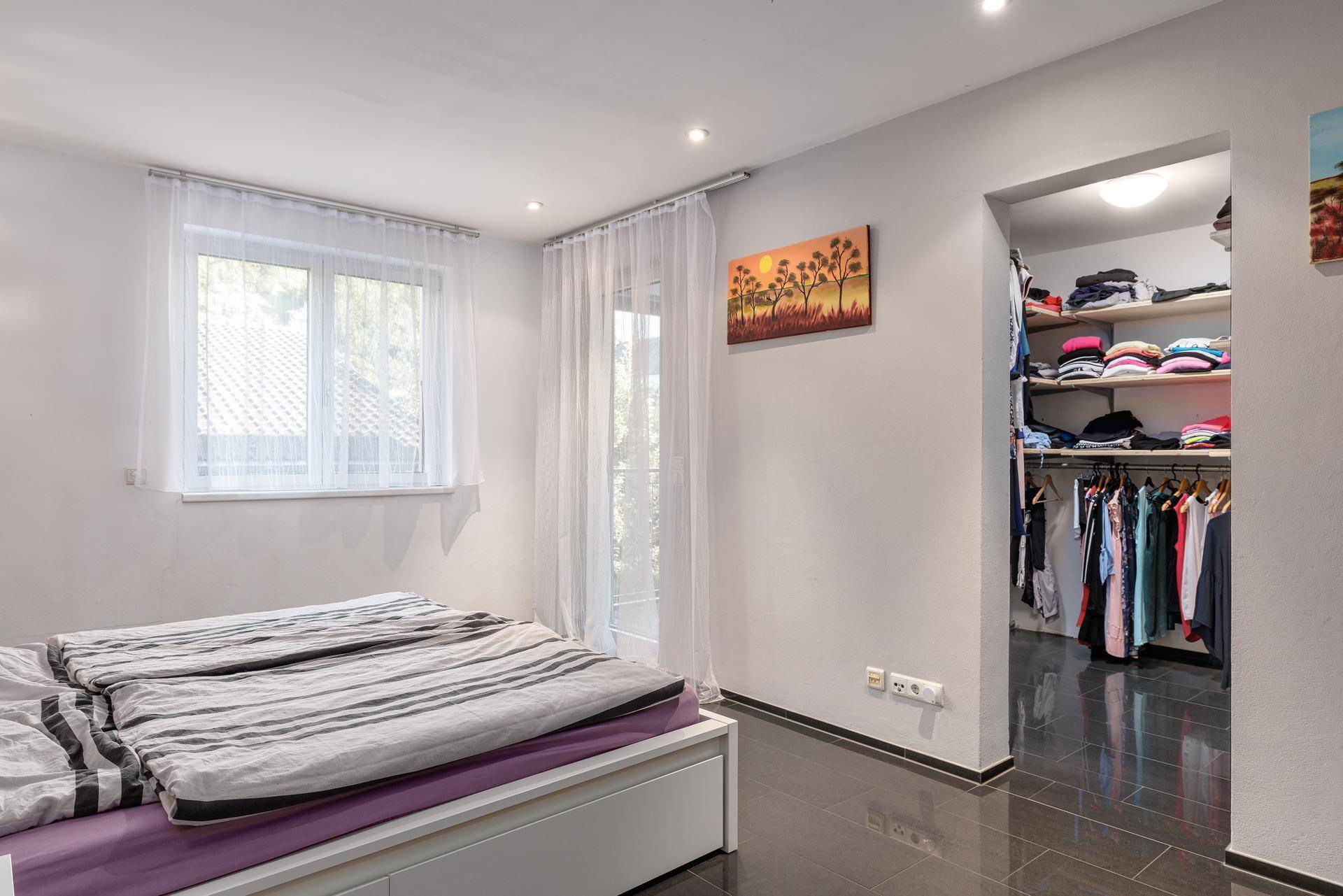 Schlafzimmer mit hellem Ambiente und direktem Zugang zu einem begehbaren Kleiderschrank.