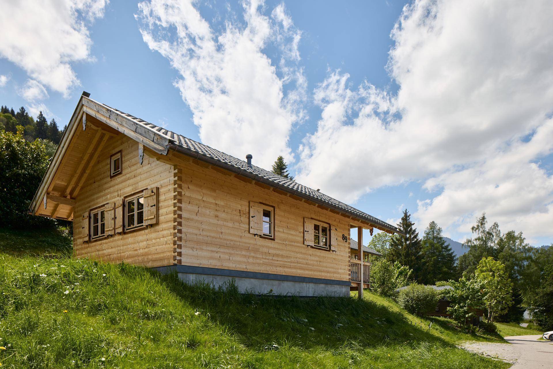 Seitenansicht eines Holzchalets mit Holzwänden und Satteldach in ländlicher Umgebung.
