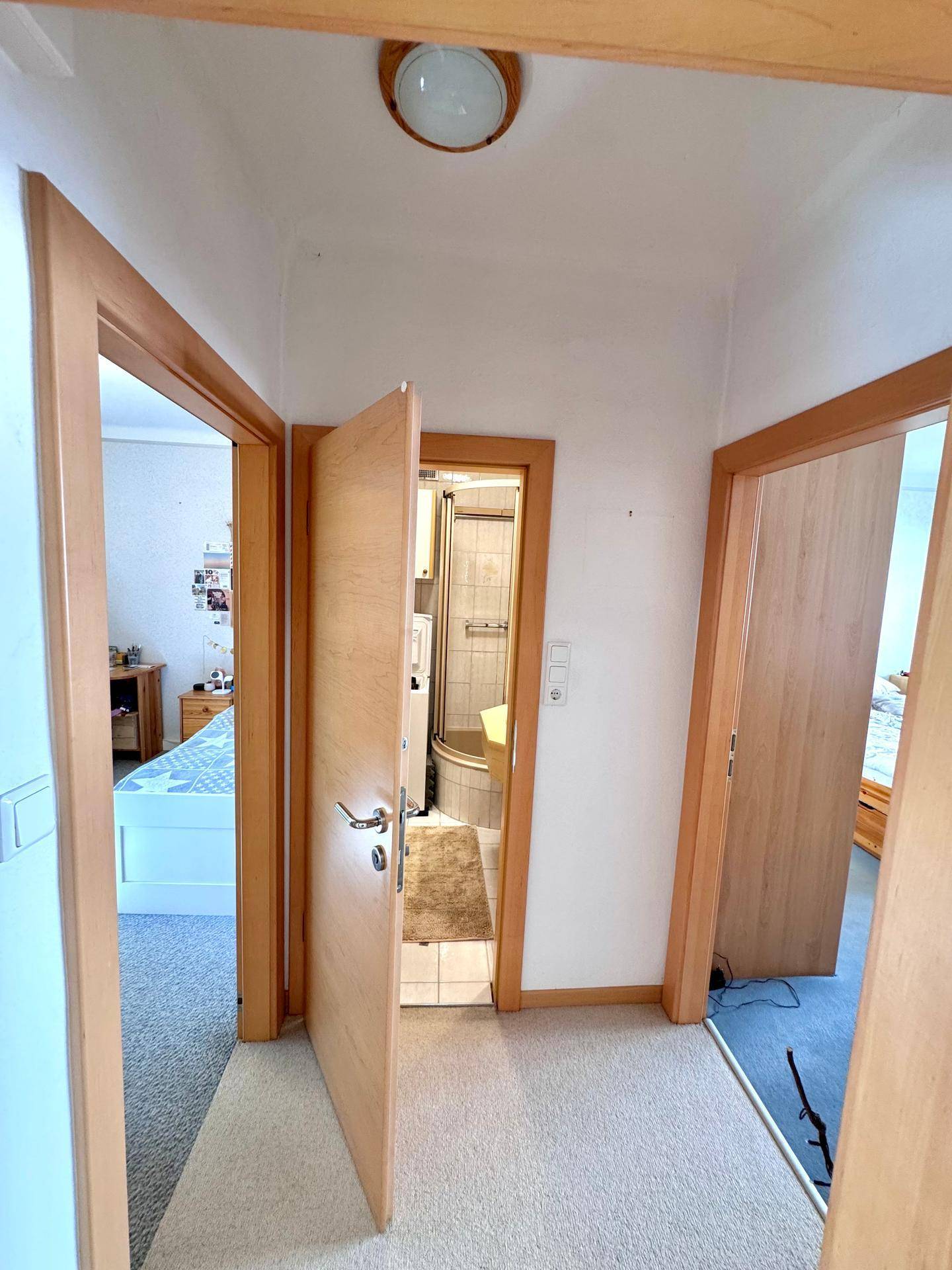 Flur mit Zugang zu Schlafzimmer und Badezimmer, ausgestattet mit Teppichboden.