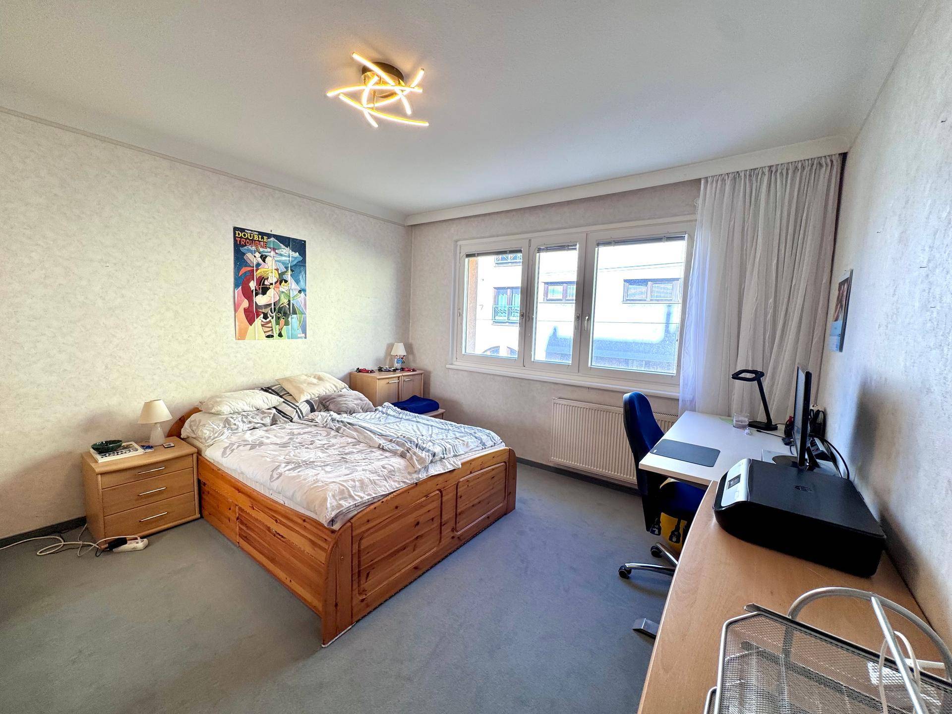Geräumiges Schlafzimmer mit Doppelbett, Schreibtisch und Blick nach draußen.
