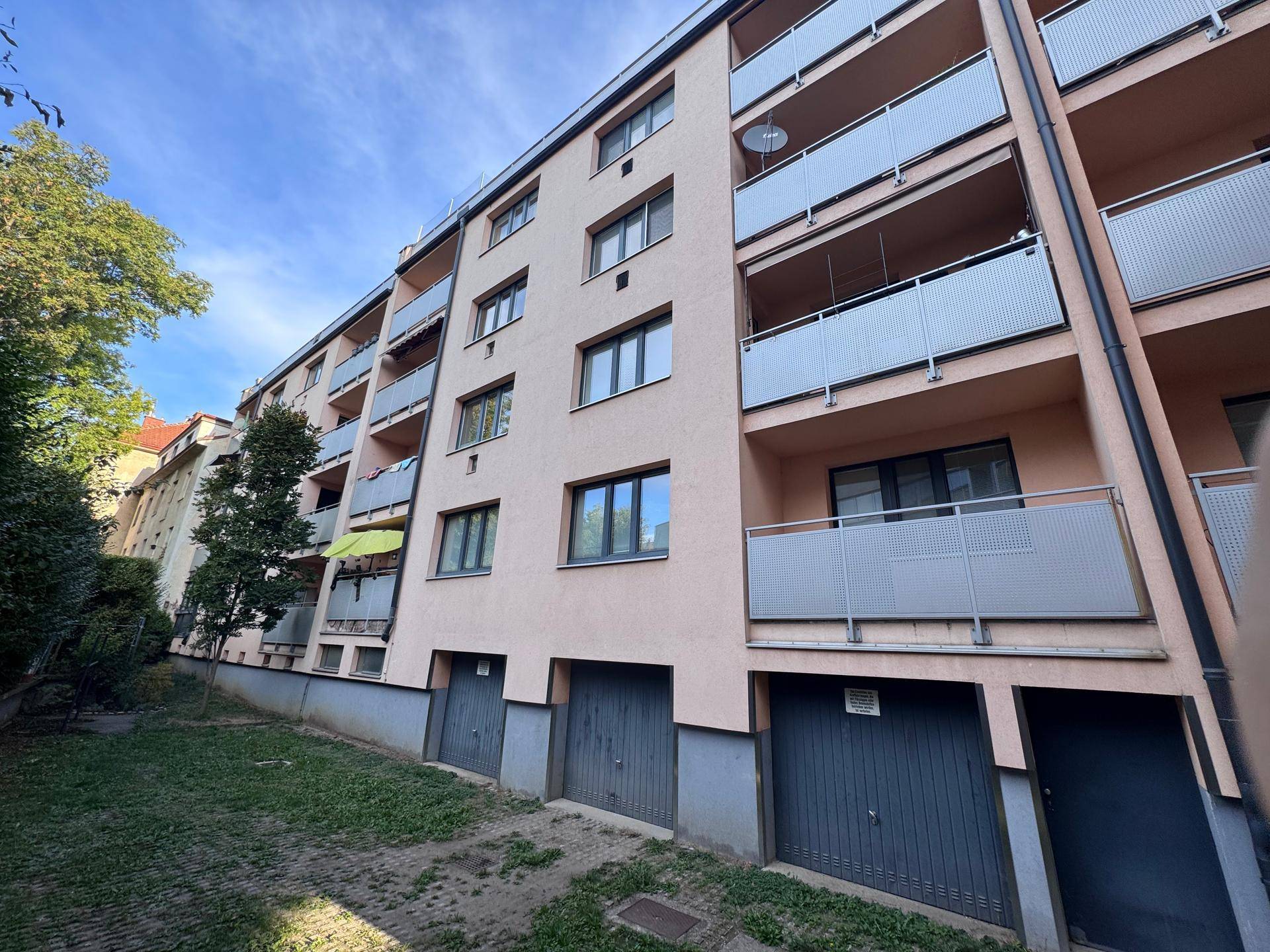 Fassade des Mehrfamilienhauses mit Balkonen und Garagentoren im Erdgeschoss.