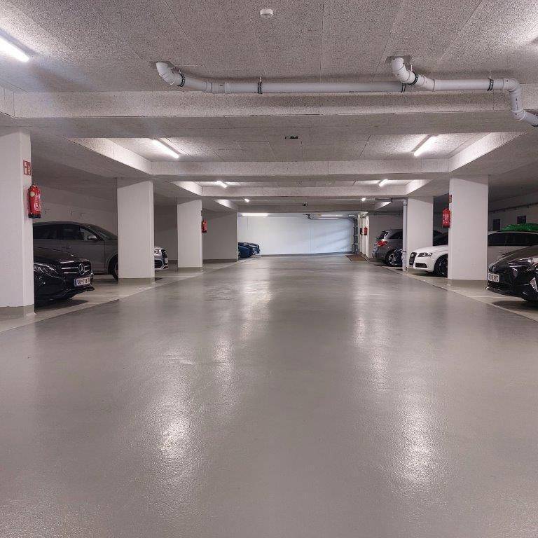 Geräumige und gut beleuchtete Tiefgarage mit mehreren Stellplätzen für Fahrzeuge.