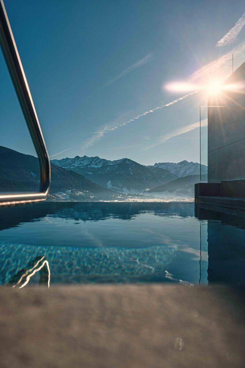 Infinity-Pool mit atemberaubendem Bergblick unter strahlend blauem Himmel und Sonnenschein.