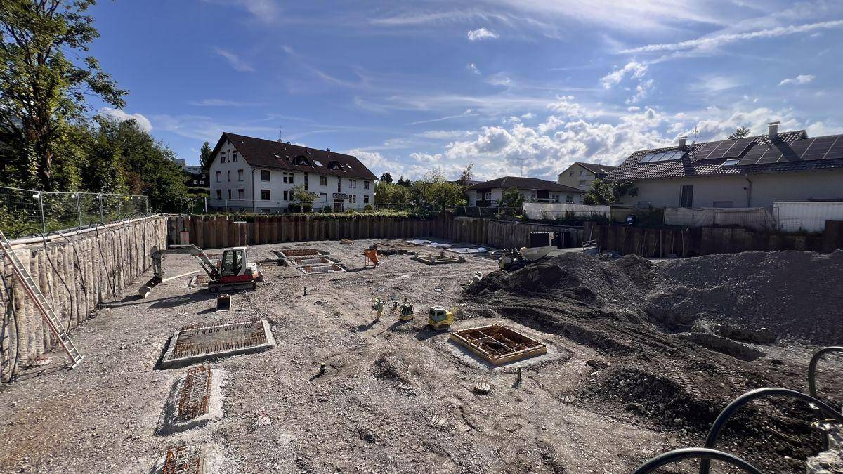 Baustelle mit ausgehobener Grube und vorbereiteten Fundamenten für den Neubau.