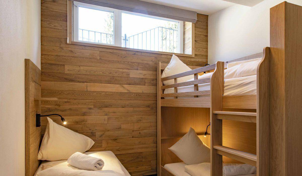 Gemütliches Schlafzimmer mit Etagenbetten und Holzwänden, ideal für Kinder oder Gäste.