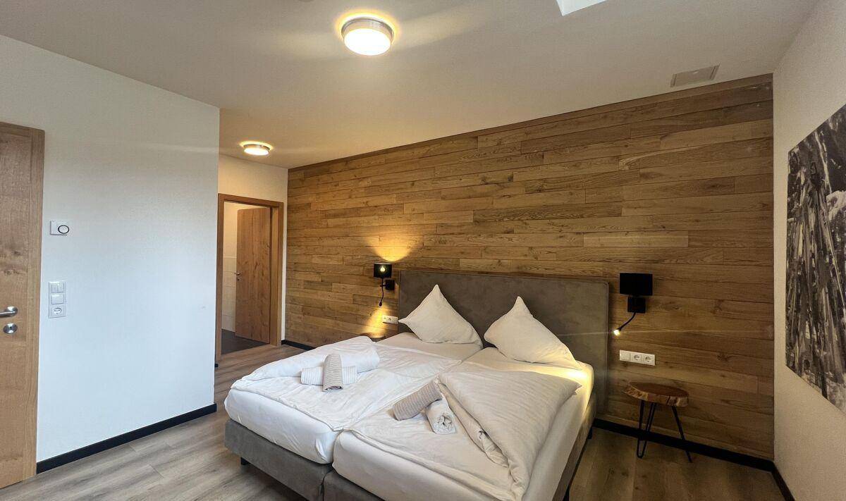 Geräumiges Schlafzimmer mit Doppelbett und einer stilvollen Holzwand als Akzent.