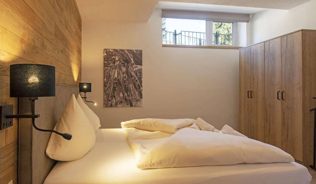 Komfortables Schlafzimmer mit Doppelbett, Holzwand und integriertem Kleiderschrank.