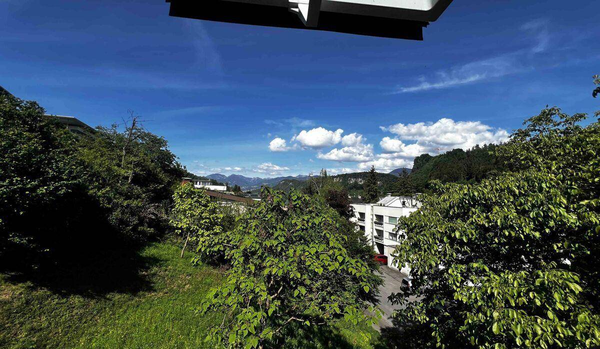 Weitläufiger Blick über grüne Hügel und Berge unter einem strahlend blauen Himmel.