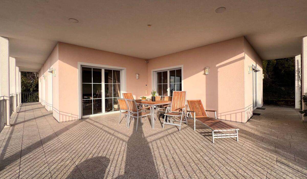Sonnige Terrasse mit Essbereich und Liegestuhl, ideal für entspannte Stunden im Freien.