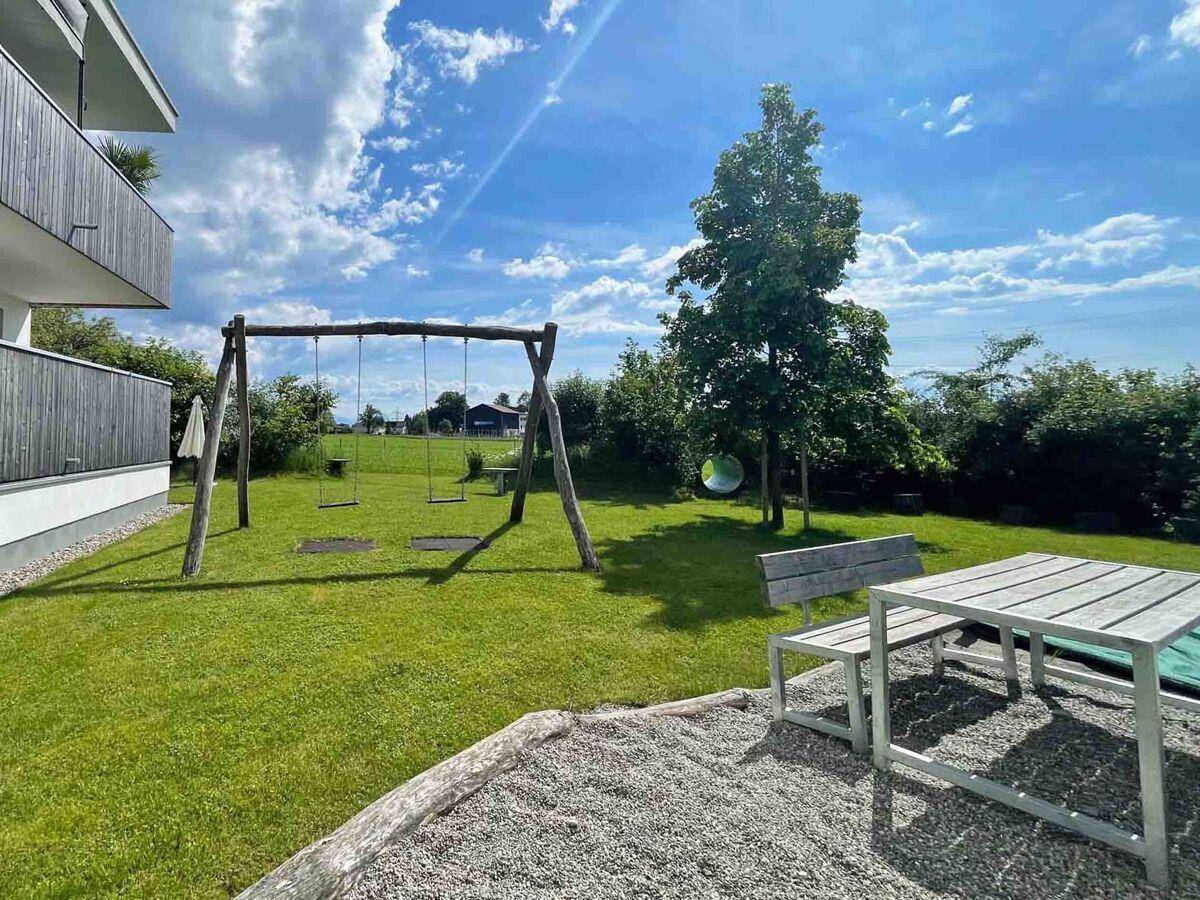 Gemeinschaftlicher Gartenbereich mit Schaukeln, Picknicktisch und viel Grünfläche für Kinder.