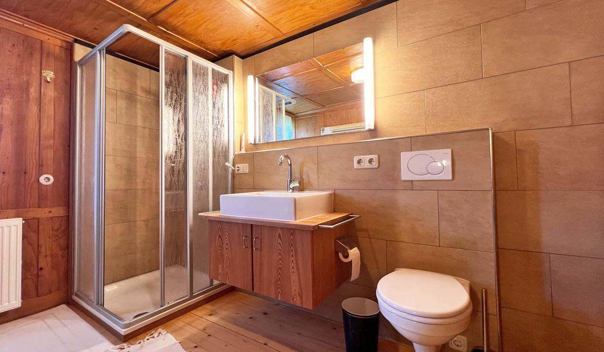 Modernisiertes Badezimmer mit Duschkabine, Waschbecken und Wand-WC in neutralen Farbtönen.