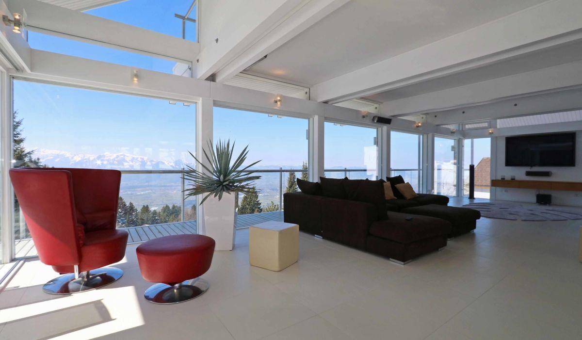 Helles Wohnzimmer mit bodentiefen Fenstern, die einen atemberaubenden Blick auf die Berge bieten.