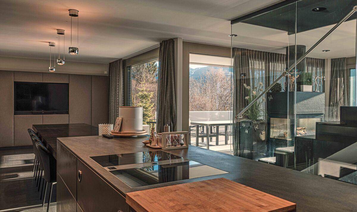 Moderne Küche mit Kochinsel und Essbereich, offen zum Wohnzimmer und mit Zugang zur Terrasse.