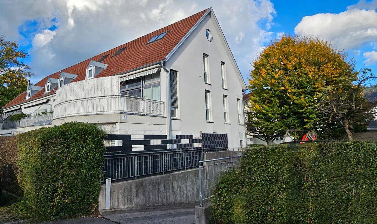 Außenansicht eines Wohngebäudes mit rotem Ziegeldach, weißer Fassade und barrierefreiem Zugang über eine Rampe.